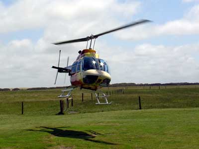 Helicopter just after takeoff, hovering above a green field